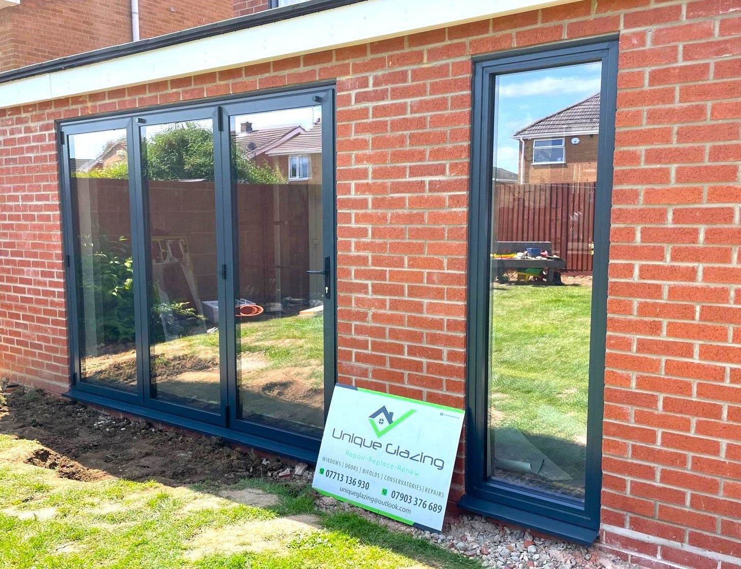 Dark grey aluminium glazing and doors on a new brick extension