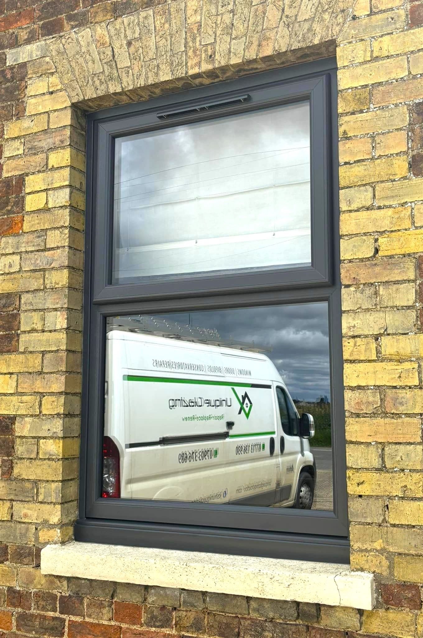 A tall dark grey aluminium window in a yellow brick wall