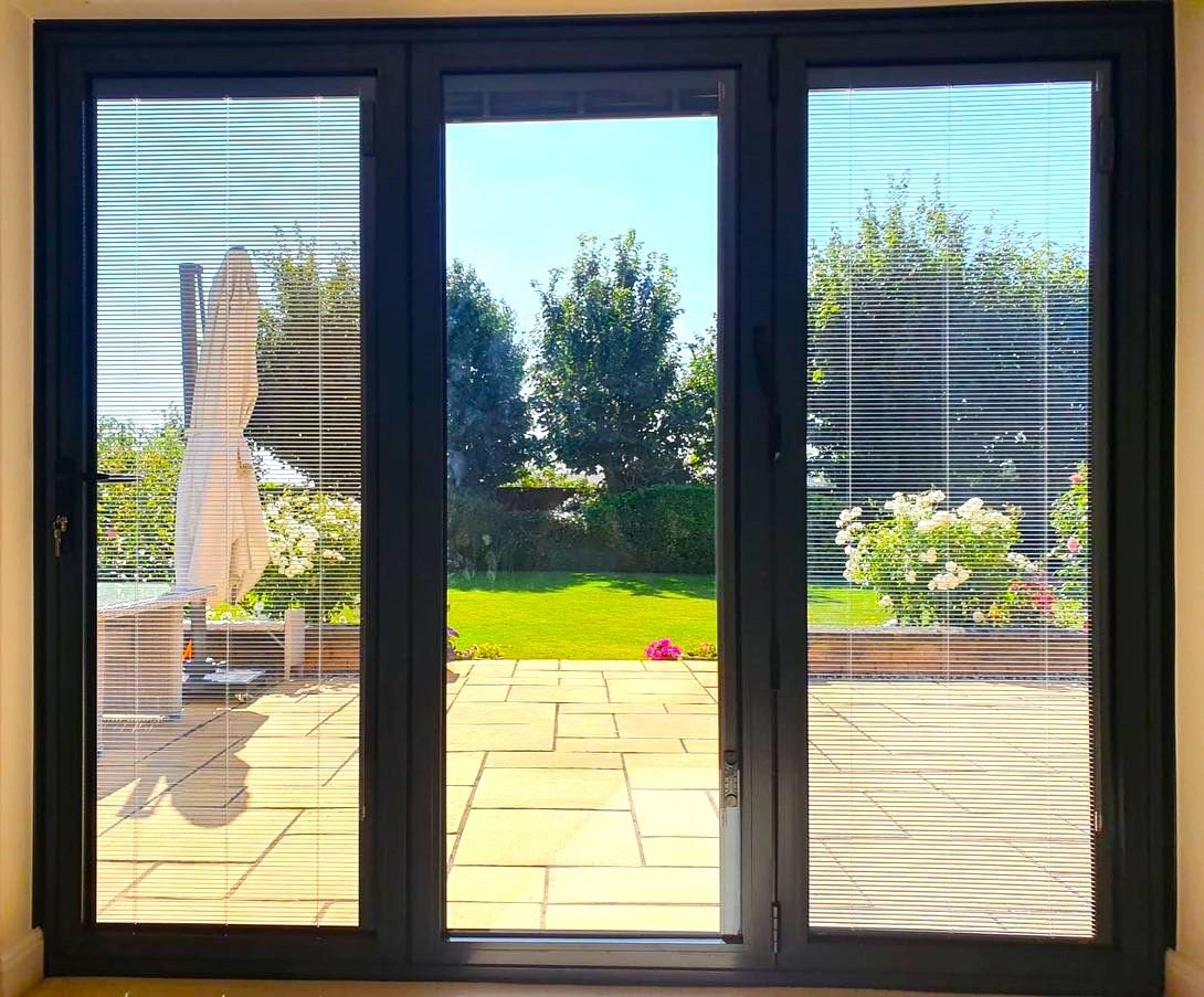 Black bifold doors looking out onto a patio and garden