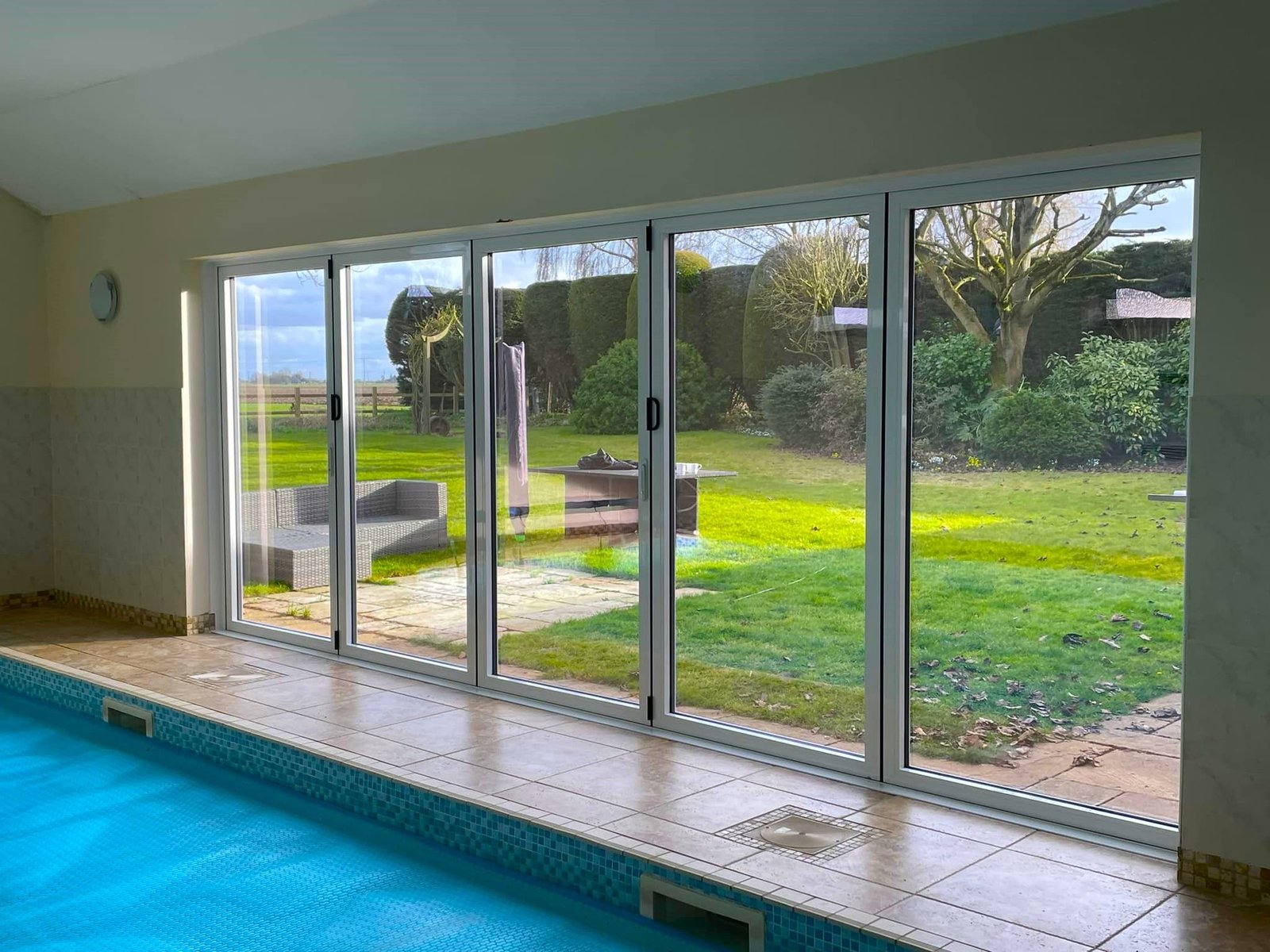 Bifold doors along the side of an indoor swimming pool