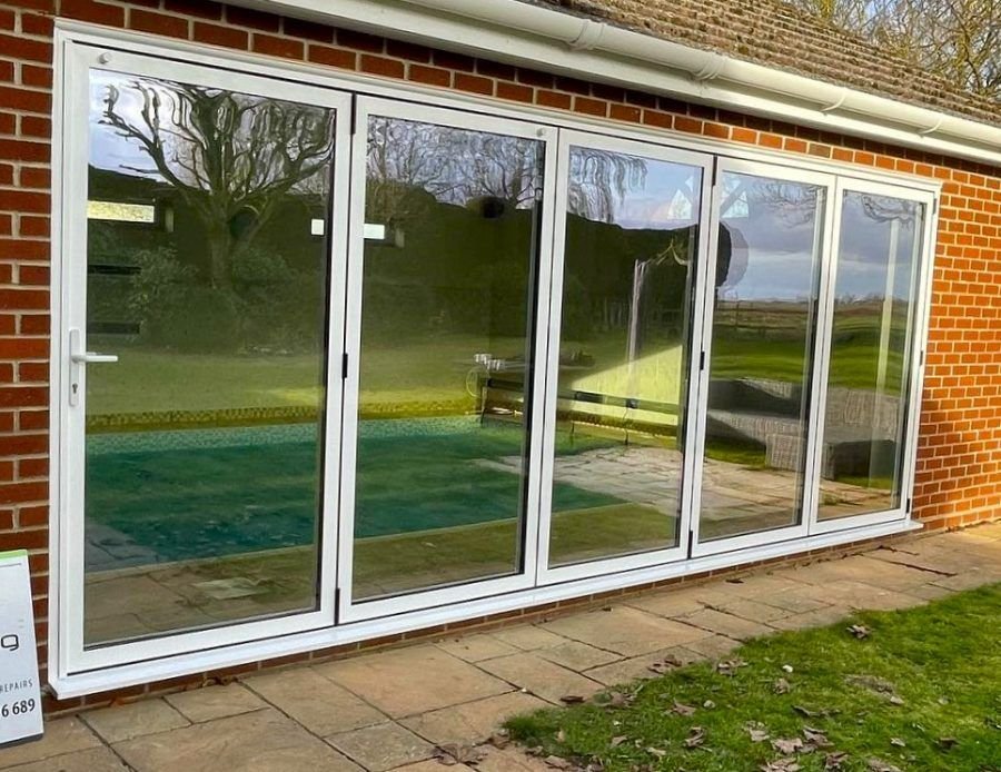 White bifold doors across the back of a brick house