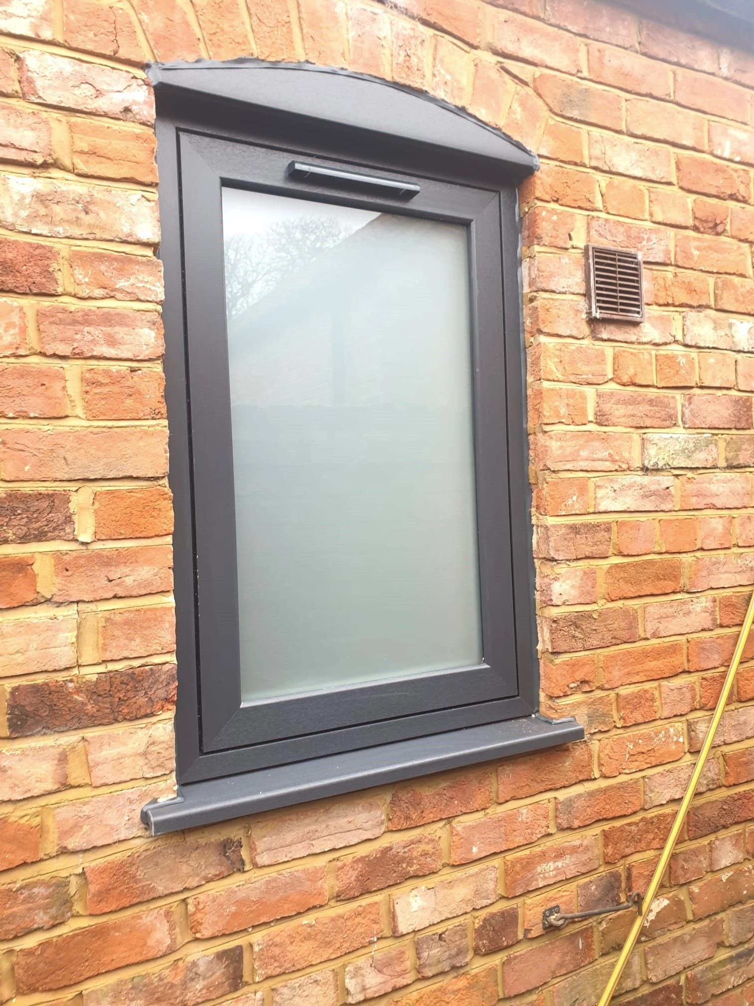 A single grey casement window with frosted glass