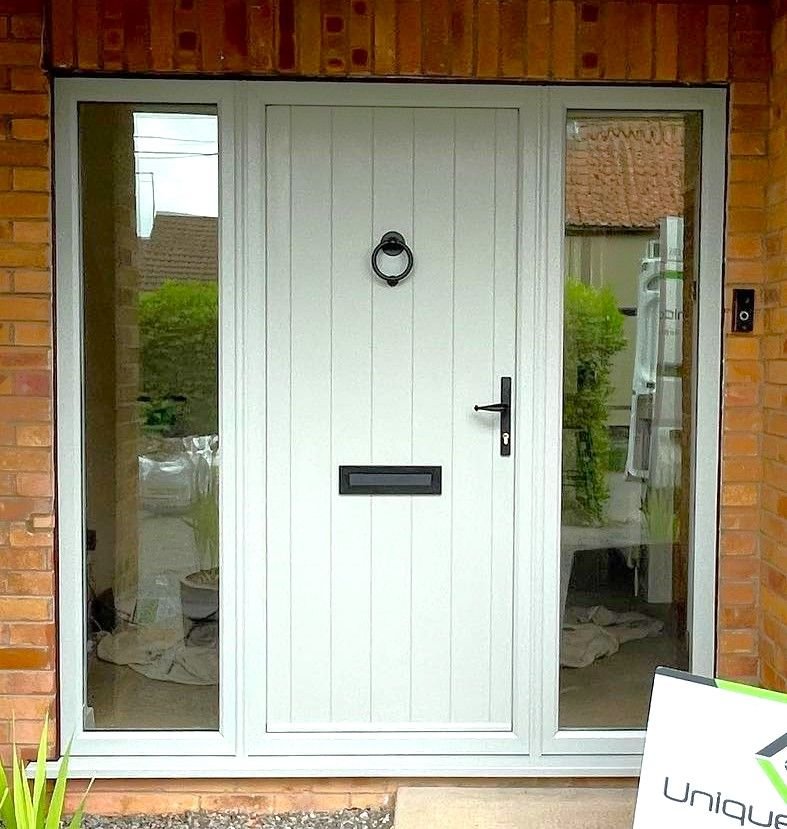 A sage green front door with glass side panels