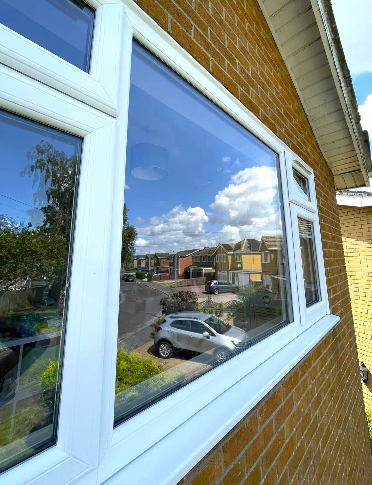 A white window on the corner of a brick house