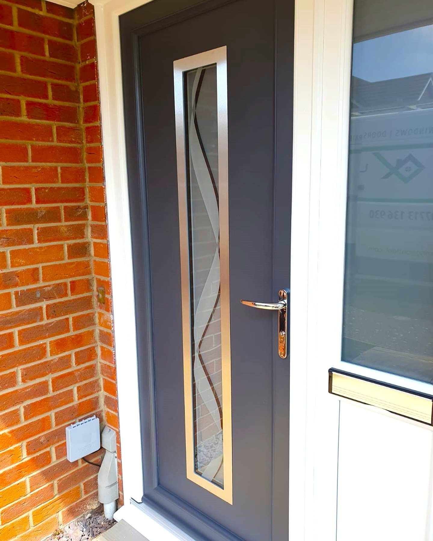 A grey front door with a decorative glass panel