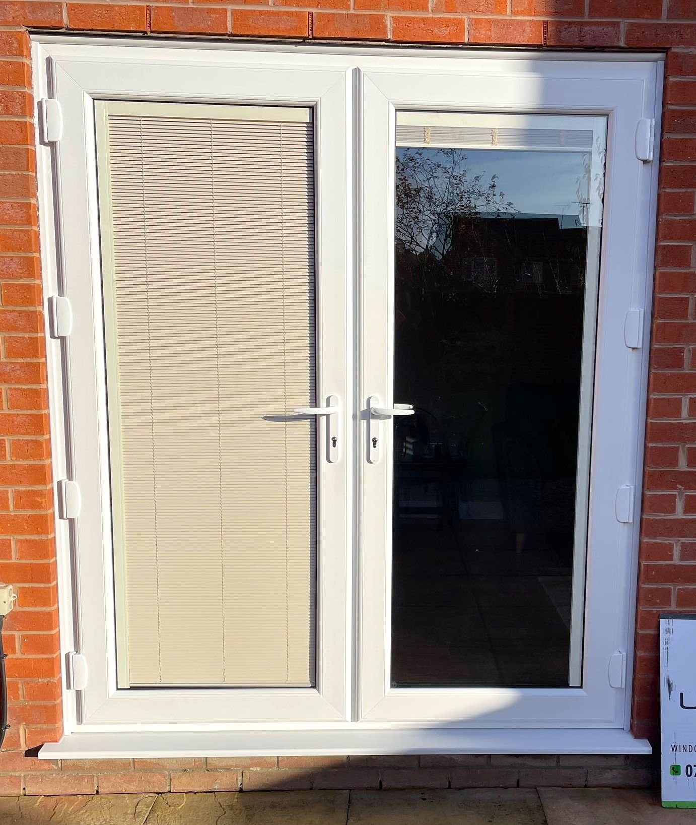 White French doors with blinds in a red brick wall