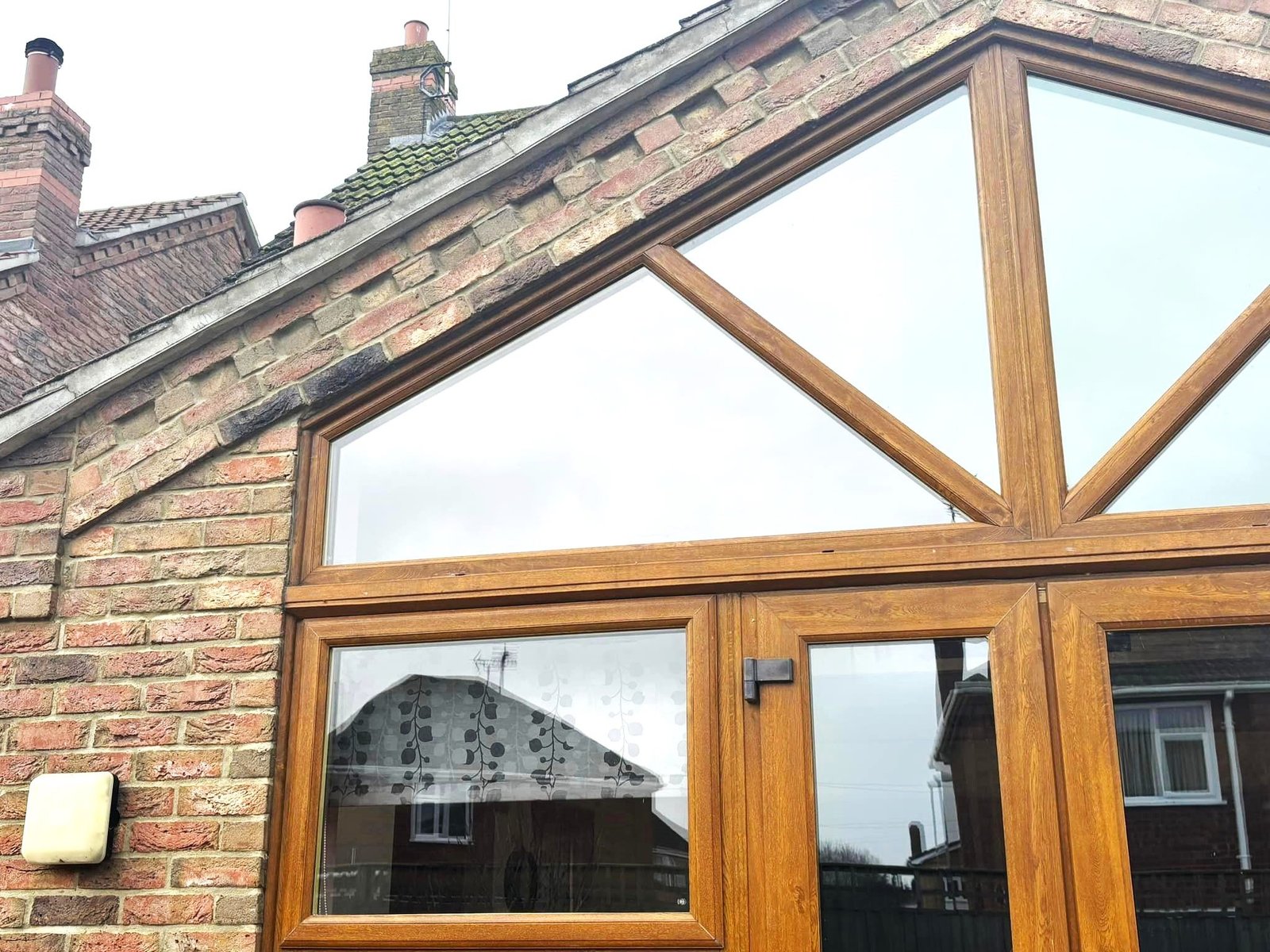 Oak-effect windows filling a gable end above French doors