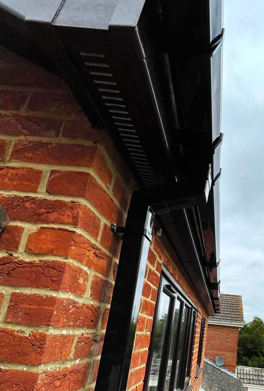 A black downpipe and gutter on a brick wall