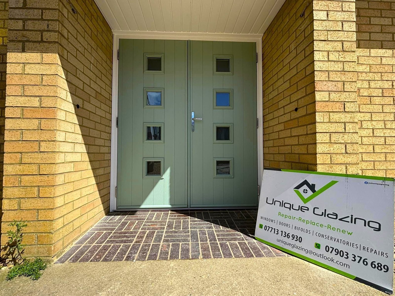 Close-up of new sage green double doors with small glass panels