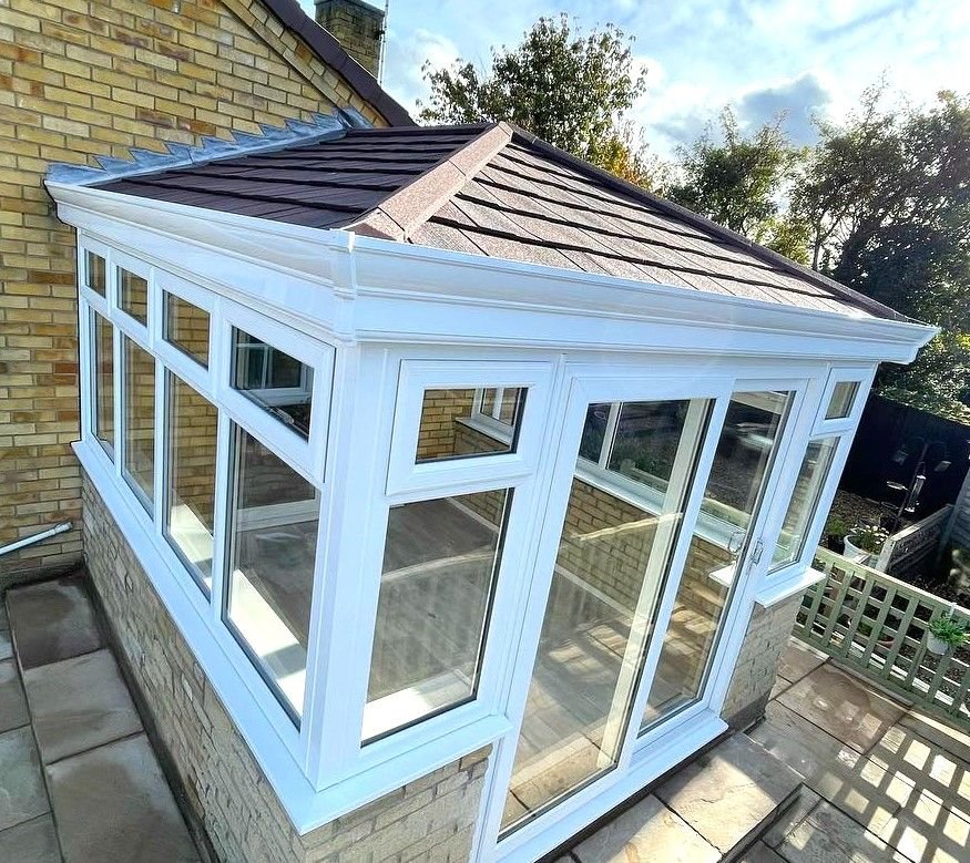 A white conservatory with a tiled warm roof