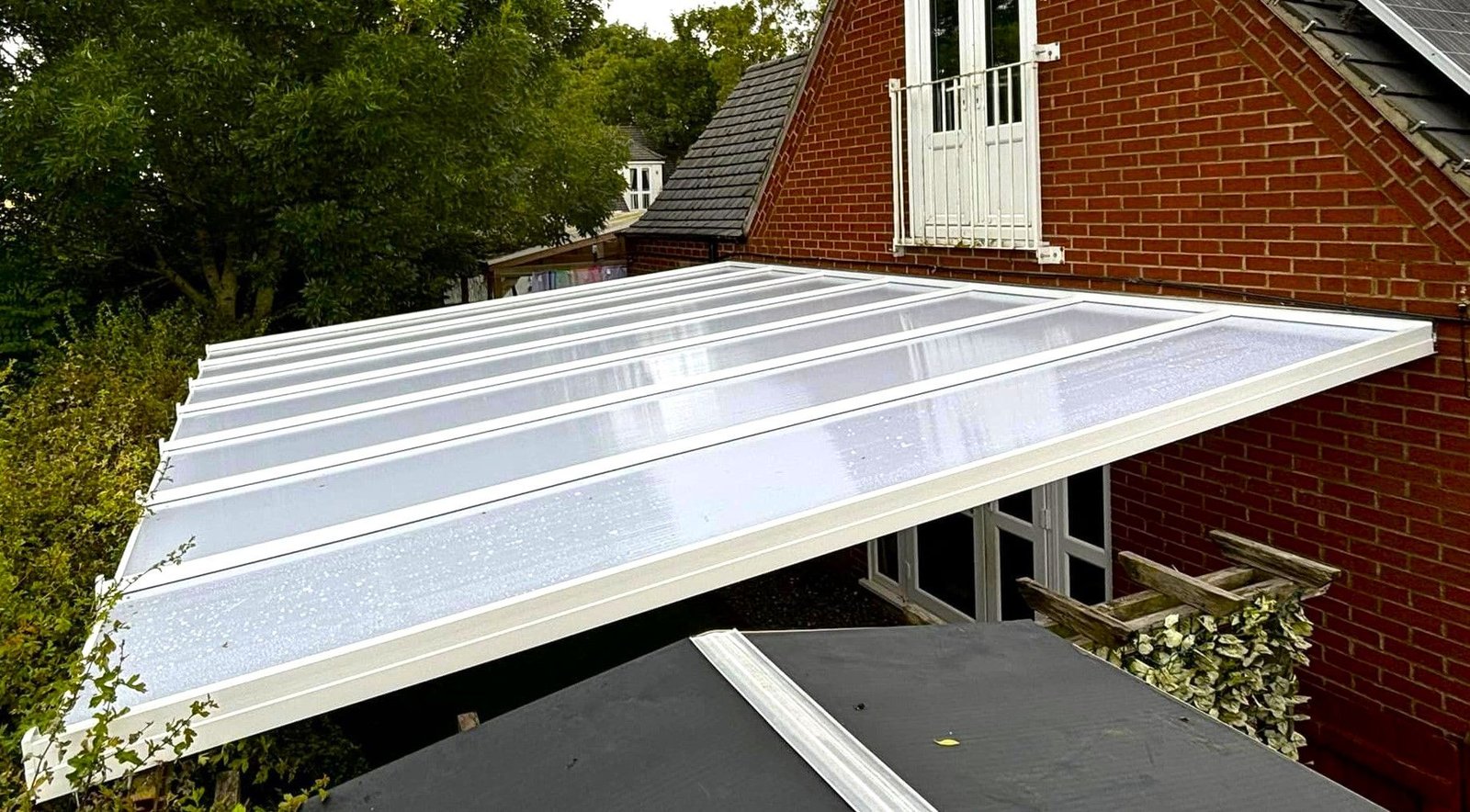 A lean-to with a translucent sloping roof against a brick house