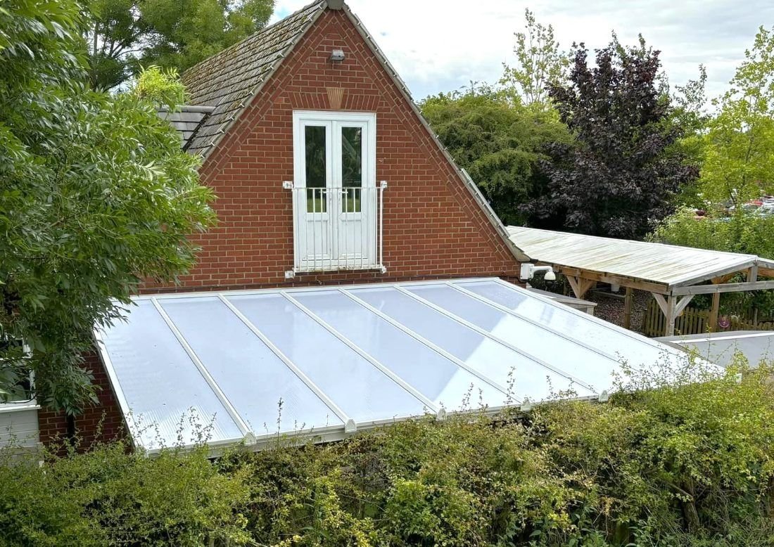A lean-to with a sloping roof against a brick house