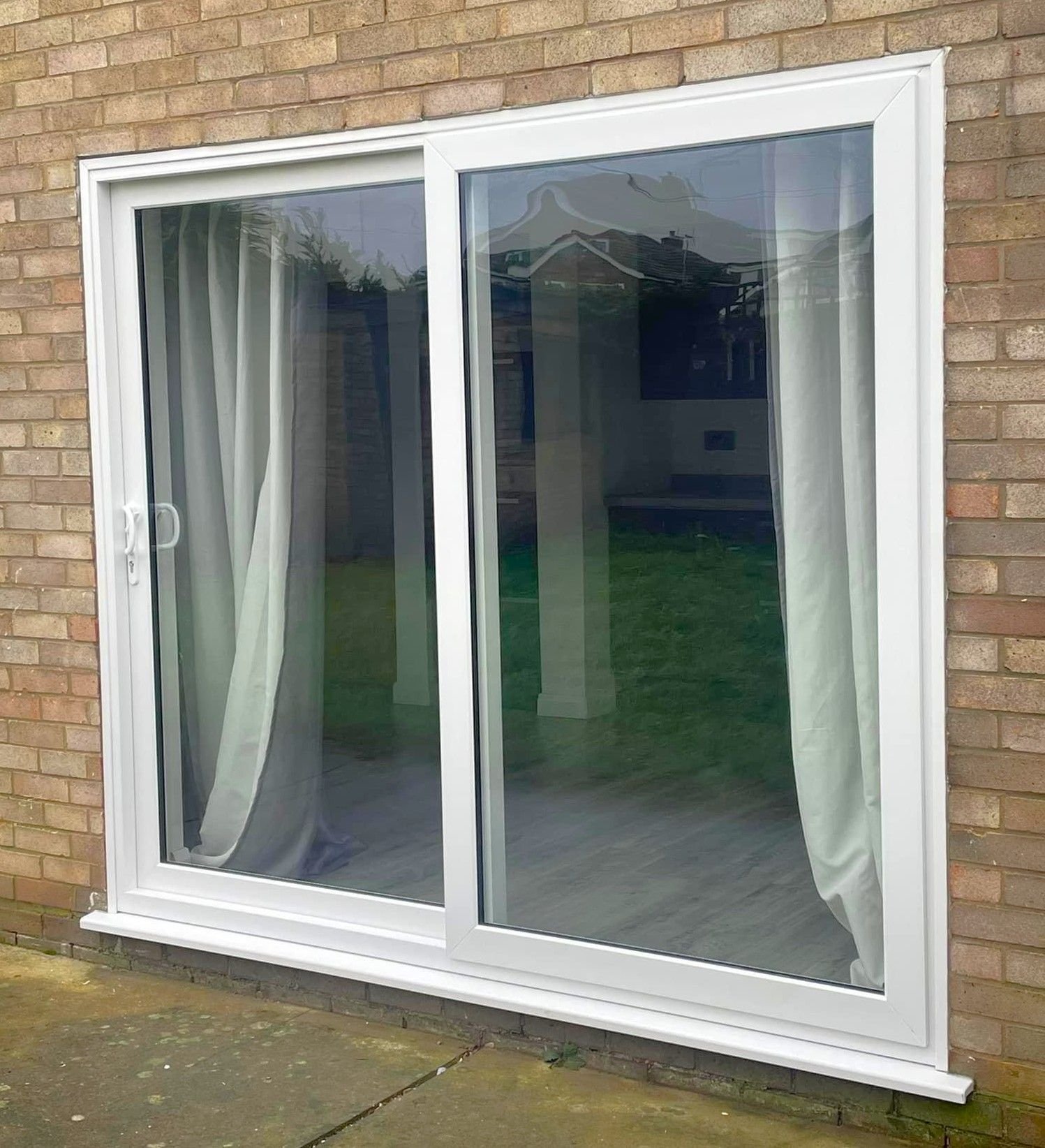 White sliding patio doors with curtains, seen from outside