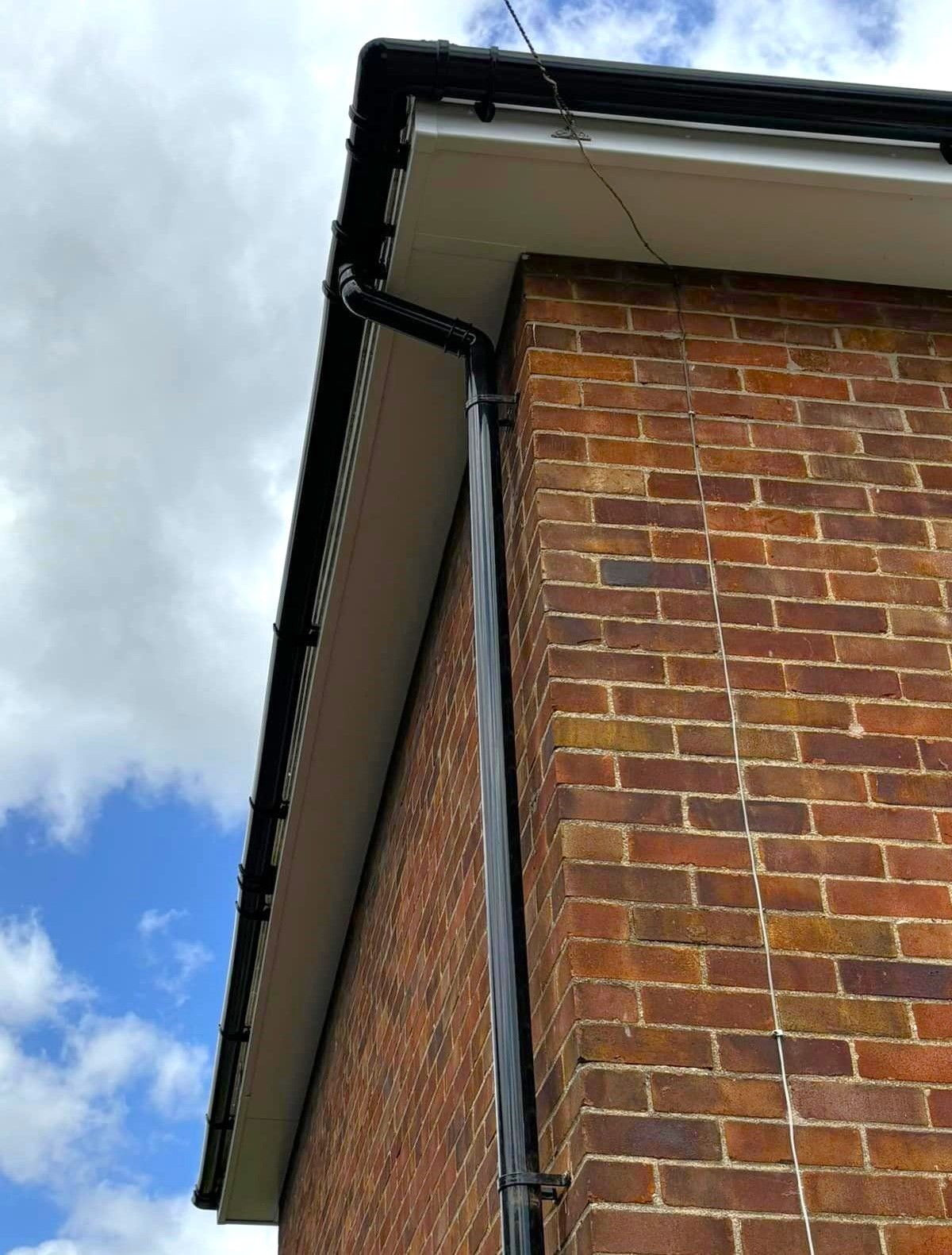 White soffits and black guttering on the corner of a brick house