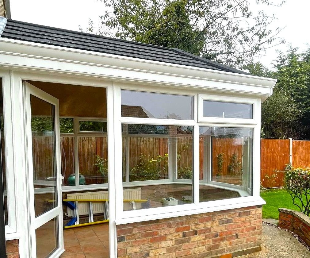 A white conservatory with its door open onto the garden